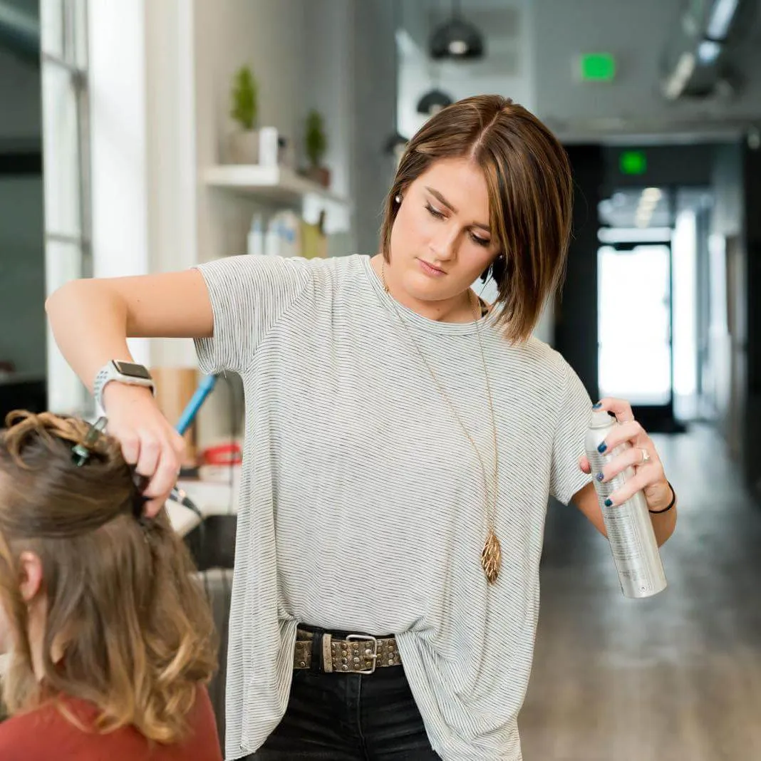 Frau in grauem Top hält graue Sprühflasche
