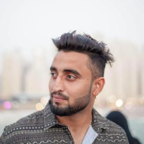 Mann mit Irokesenschnitt vor einem Gewässer stehend